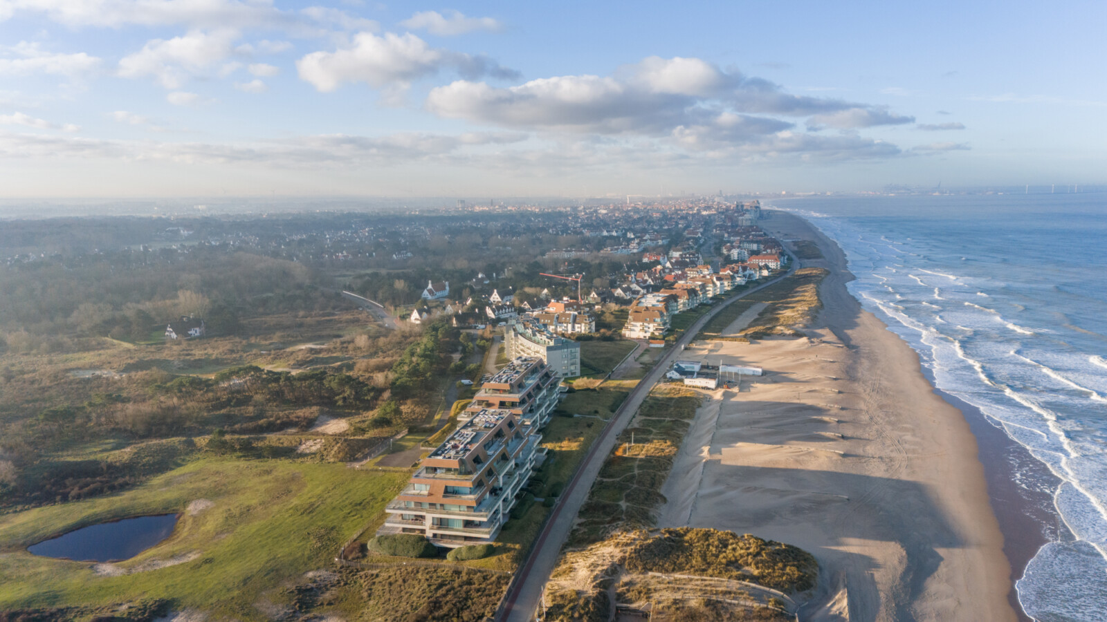ALT tekst Luchtfoto van residentie Finis Terrae aan de Wandeldijk in het Zoute, met het strand en de zee ernaast.
